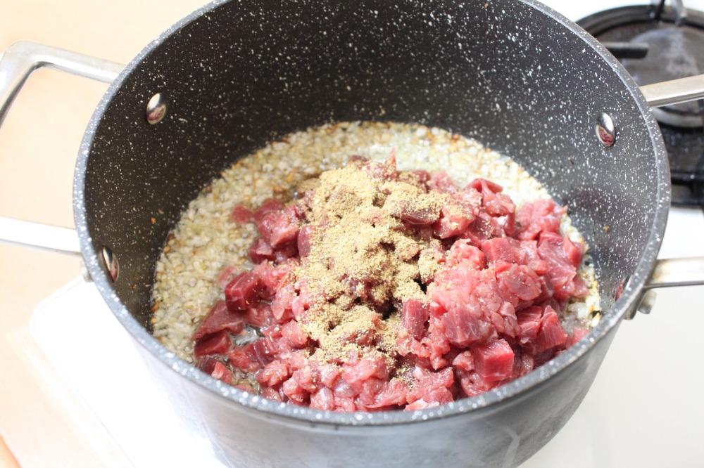 К луку отправить мелко нарезанное мясо, курдючный жир и специи