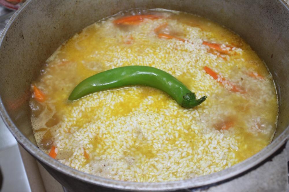Равномерно распределите промытый рис поверх моркови